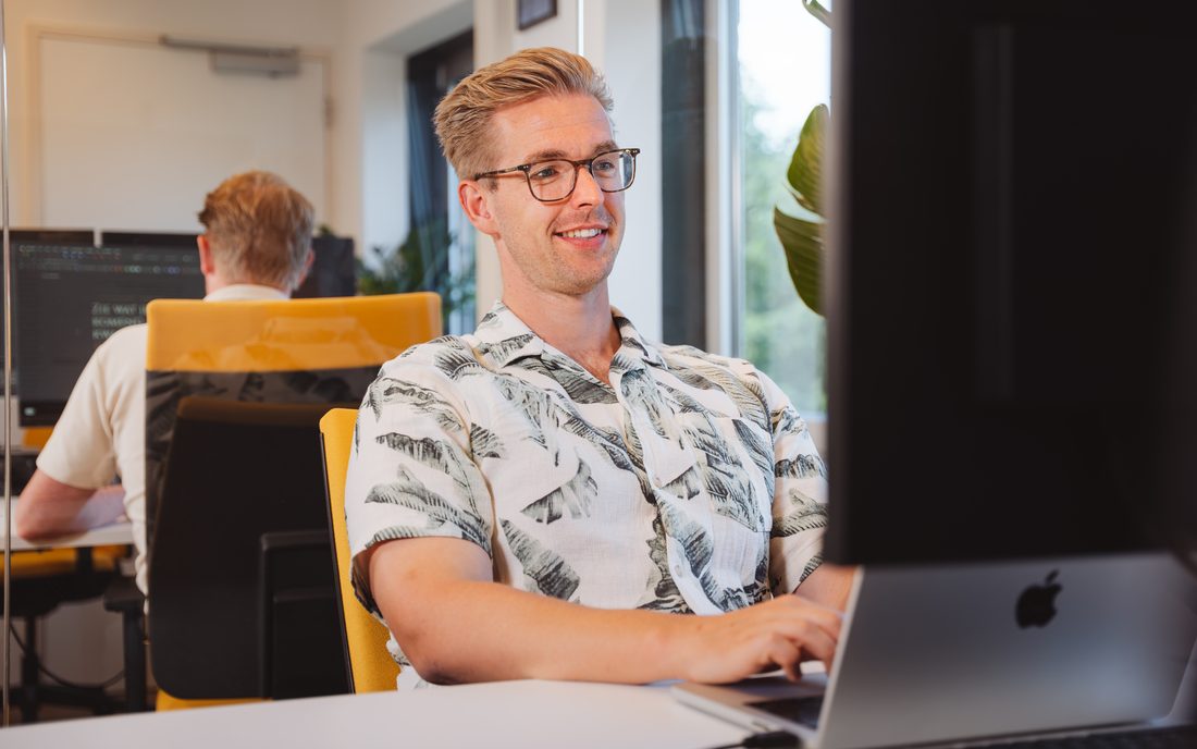 Een ontwikkelaar van Empathree werkt aan software achter een laptop en een groot scherm